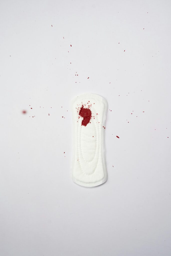 A white sanitary pad with a red bloodstain, highlighting menstruation and feminine hygiene.